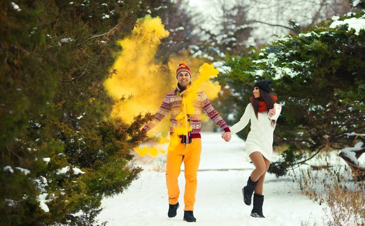 Молодая пара на фотосессии с желтым дымом зимой